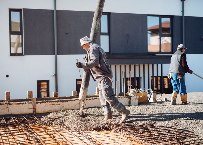 Industrial worker laying concrete with automatic tube pump. Workman on site with mortar and construction activities